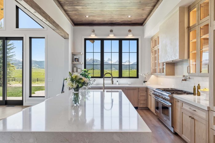 A kitchen island beneath mountain-view windows edited by AutoHDR V3