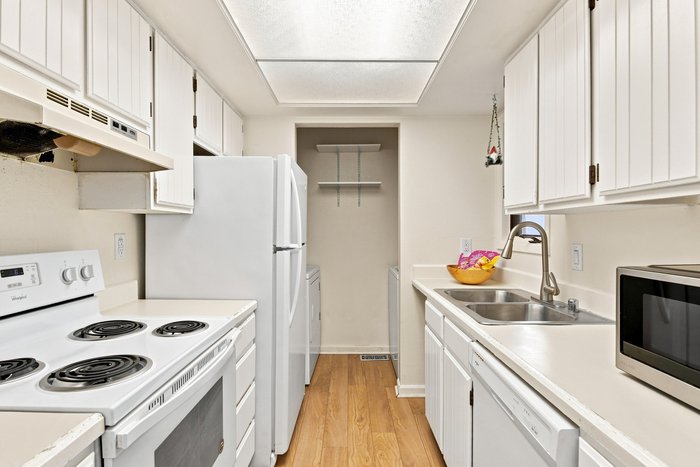 A galley kitchen with white cabinets and a skylight edited by AutoHDR Iris