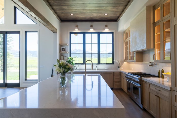 Mid bracket exposure of a kitchen island beneath mountain-view windows