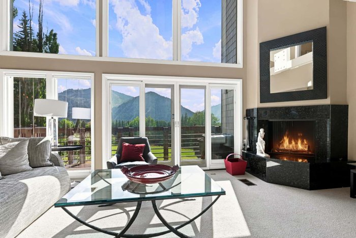 A living room with tall windows and a fireplace edited by AutoHDR Iris